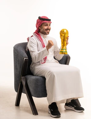 رجل سعودي يحمل مجسم كأس العالم في الاستوديو