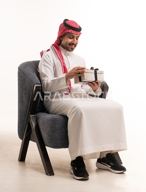 رجل سعودي بالثوب التقليدي يحمل صندوق هدايا