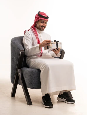 رجل سعودي بالثوب التقليدي يحمل صندوق هدايا