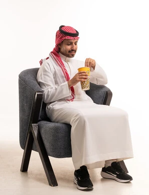 رجل سعودي بالزي التقليدي يأكل الفشار