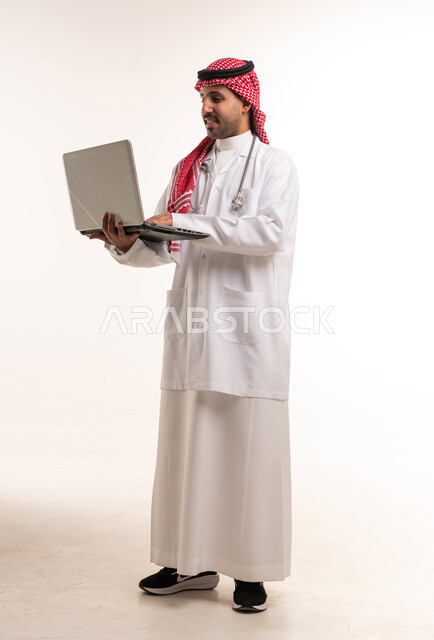 طبيب سعودي ممارس صحي يستخدم لابتوب بخلفية بيضاء طبي