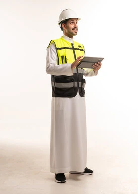 مهندس سعودي بالثوب ومعدات السلامة يحمل جهاز لوحي