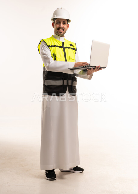مهندس سعودي يحمل لابتوب بملابس السلامة