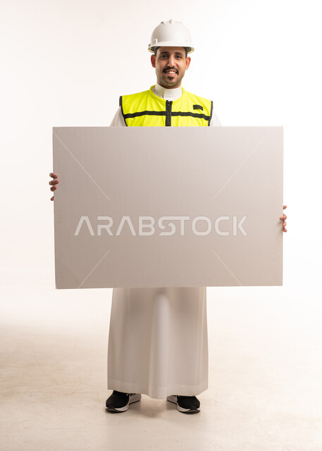 مهندس سعودي بزي السلامة يحمل لوحة إعلانية بيضاء فارغة