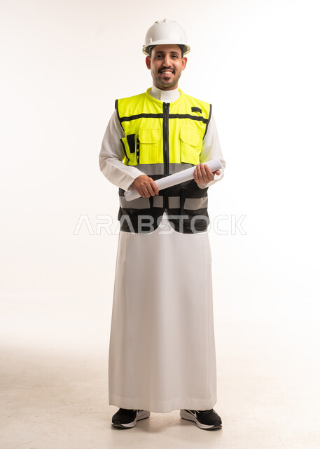 مهندس سعودي بالثوب يحمل مخطط بناء هندسي