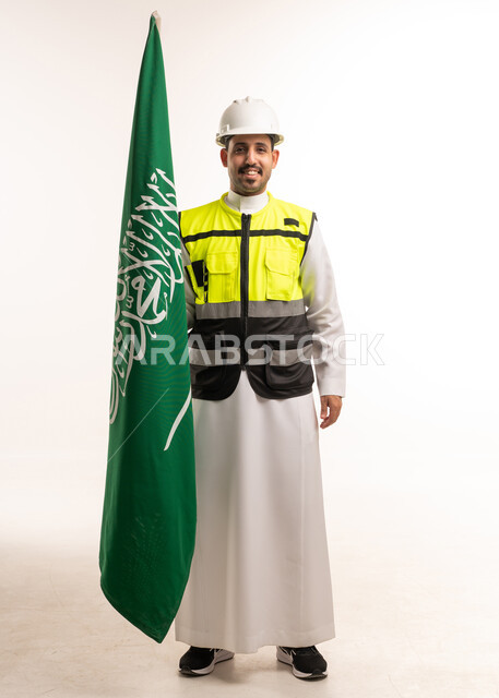 مهندس سعودي بمعدات السلامة يحمل العلم الوطني
