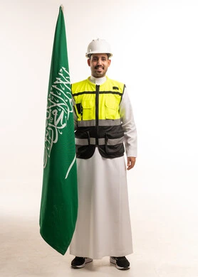 مهندس سعودي بمعدات السلامة يحمل العلم الوطني