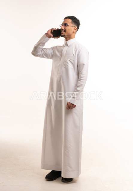 رجل سعودي بالثوب التقليدي يتحدث عبر الهاتف المحمول