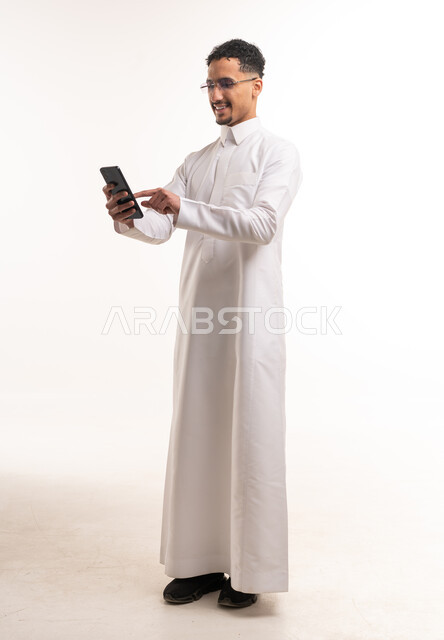رجل سعودي بالثوب الأبيض يستخدم الهاتف الذكي