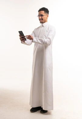 Saudi Man in White Thobe Using Smartphone