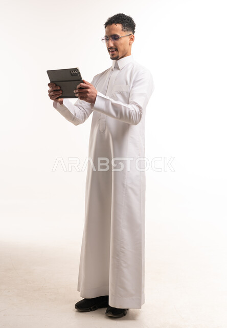 رجل سعودي بالثوب يستخدم جهاز لوحي في الاستوديو