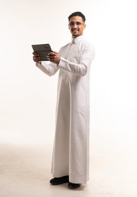 رجل سعودي يرتدي الثوب التقليدي ويستخدم جهاز لوحي رقمي