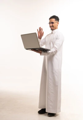 رجل سعودي بالثوب يلوح أمام شاشة اللابتوب