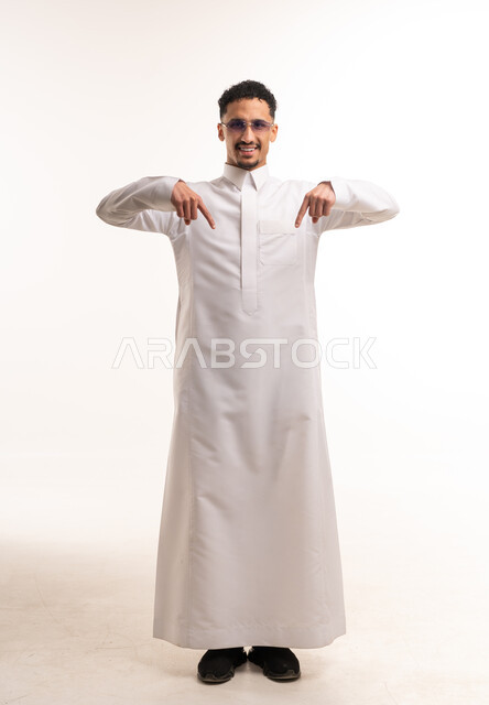 رجل سعودي بالثوب الأبيض يشير للأسفل بخلفية بيضاء
