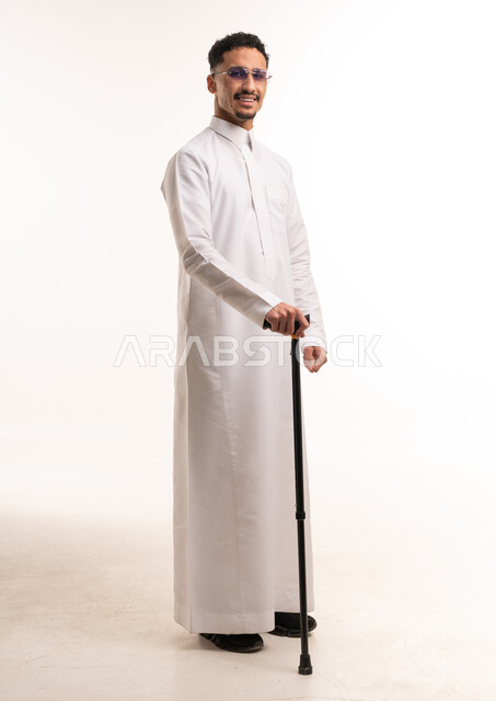 رجل سعودي بالثوب الأبيض يمسك عصا مشي