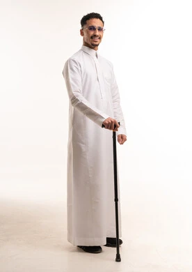 رجل سعودي بالثوب الأبيض يمسك عصا مشي