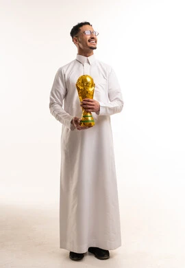 رجل سعودي بالثوب الأبيض يحمل كأس العالم الذهبي