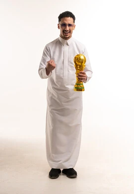 رجل سعودي بالثوب الأبيض يحمل كأس العالم الذهبي