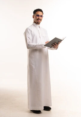 رجل سعودي بالثوب التقليدي يحمل كتاباً في الاستوديو