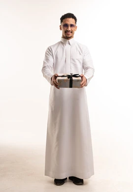 رجل سعودي يرتدي الثوب التقليدي يحمل صندوق هدايا أبيض