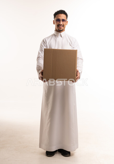 رجل سعودي بالثوب يحمل صندوق كرتوني في الاستوديو