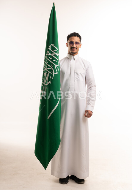 رجل سعودي بالثوب الأبيض مع العلم السعودي