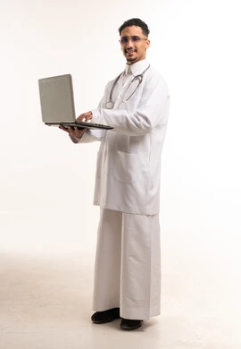 طبيب سعودي مع جهاز حاسوب محمول وسماعة طبية خلفية بيضاء