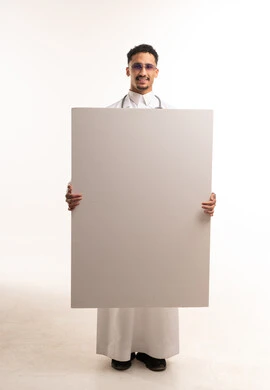طبيب سعودي يرتدي الثوب يحمل لوحة بيضاء فارغة للإعلانات