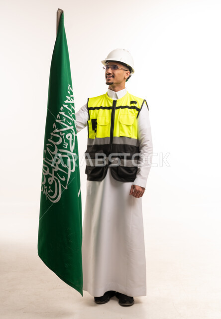 مهندس سعودي بزي السلامة يمسك علم المملكة