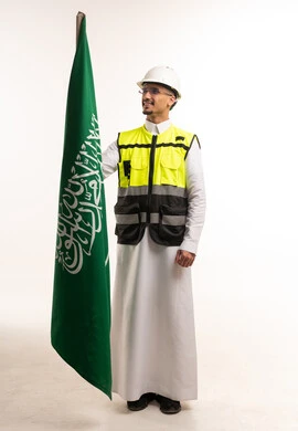 مهندس سعودي بزي السلامة يمسك علم المملكة