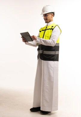 مهندس سعودي بالثوب يستخدم تابلت مع معدات السلامة