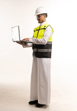 مهندس سعودي يستخدم الحاسوب بملابس السلامة والخوذة