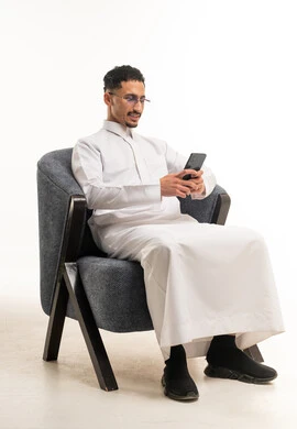 رجل سعودي بالثوب التقليدي يستخدم الهاتف الذكي