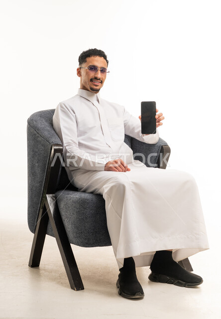 رجل سعودي بالثوب التقليدي يحمل هاتف ذكي