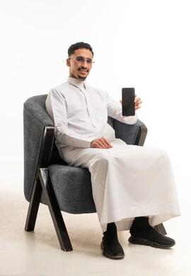 رجل سعودي بالثوب التقليدي يحمل هاتف ذكي