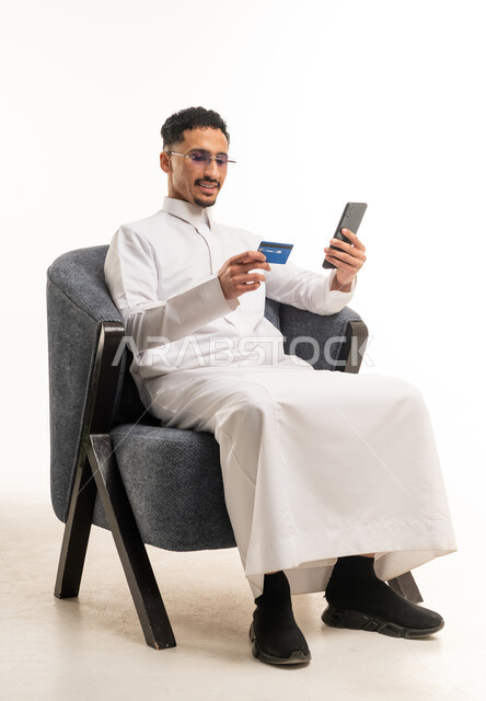 رجل سعودي بالثوب يستخدم بطاقة ائتمان وهاتف ذكي