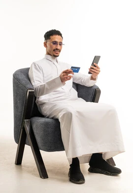 رجل سعودي بالثوب يستخدم بطاقة ائتمان وهاتف ذكي
