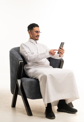 رجل سعودي بالثوب الأبيض يستخدم الهاتف الذكي
