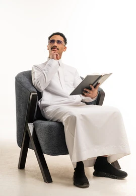 رجل سعودي بالثوب الأبيض يقرأ كتاباً في الاستوديو