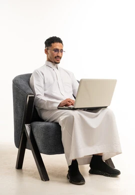 رجل سعودي بالثوب الأبيض يستخدم لابتوب في الاستوديو