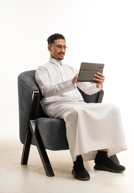 Saudi Man in Traditional Thobe Using Tablet