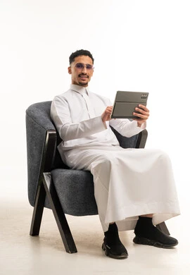 رجل سعودي بالثوب الأبيض يستخدم جهاز لوحي بالاستوديو