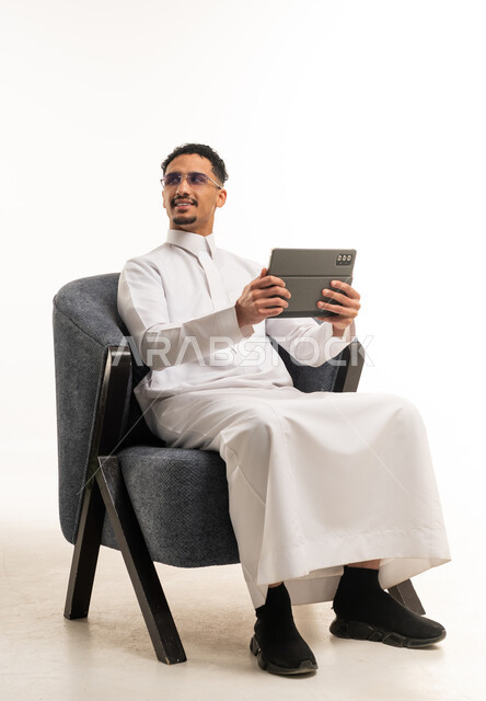 رجل سعودي بالثوب التقليدي يستخدم جهاز لوحي في الاستوديو