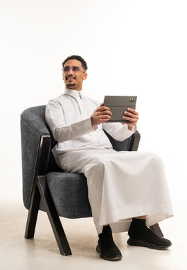 رجل سعودي بالثوب التقليدي يستخدم جهاز لوحي في الاستوديو