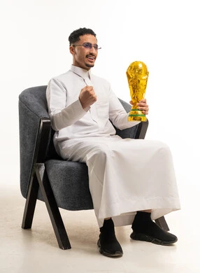 رجل سعودي بالثوب الأبيض يحمل كأساً ذهبياً