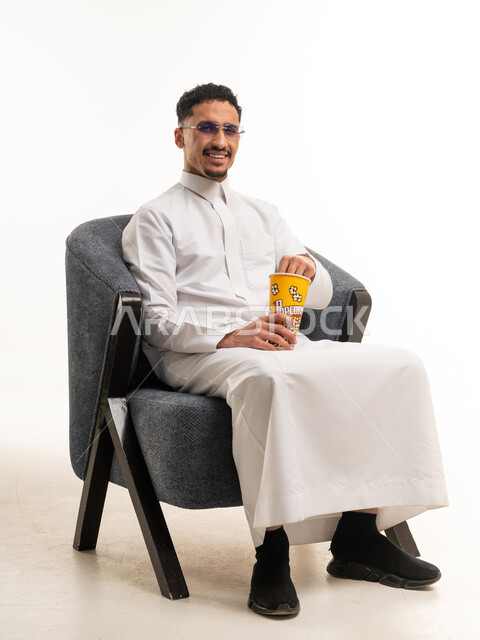 رجل سعودي بالثوب الأبيض يمسك بوعاء فشار