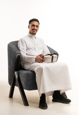 رجل سعودي بالثوب يحمل علبة هدايا في استوديو