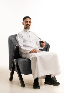 رجل سعودي بالثوب التقليدي يجلس مع مشروب بارد