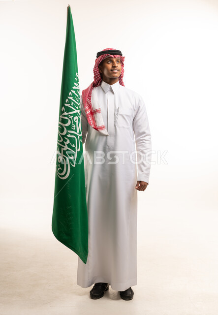 رجل سعودي يحمل العلم السعودي بالزي التقليدي
