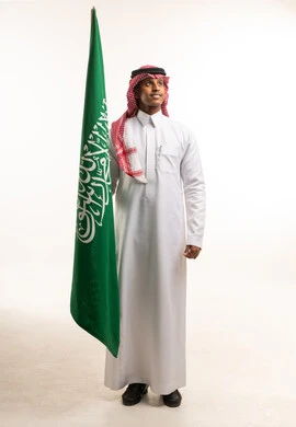 Saudi Man Holding Saudi Flag in Traditional Clothing
